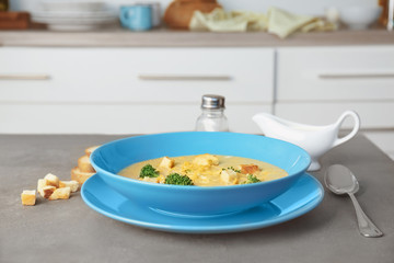 Plate with broccoli cheddar soup on table