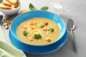 Plate with broccoli cheddar soup on table