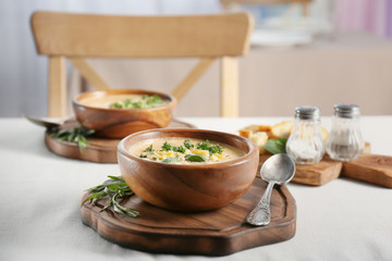 Bowl with broccoli cheddar soup on wooden board