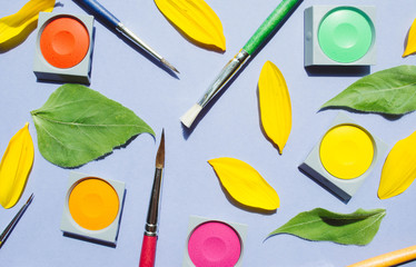 Watercolor and brushes at lila background.