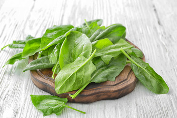 Wooden board with fresh spinach leaves on table
