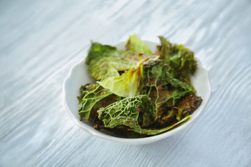 Bowl with lettuce chips on wooden table