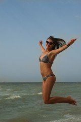 Woman smiling arms raised up to blue sky, is jumping, celebrating freedom. Positive human emotions, face expression feeling life perception success, peace of mind concept. Free Happy girl 