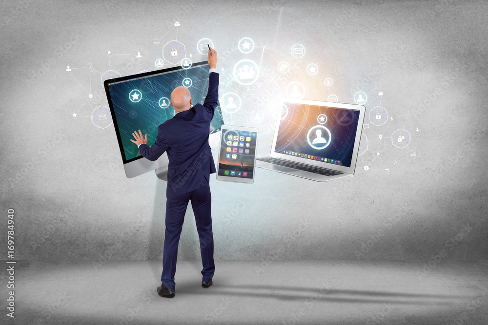 Poster businessman in front of a wall with computer and devices displayed on a futuristic interface with bu