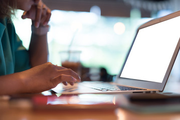 Close up Asian woman wearing pink smartwatch and working with her laptop in coffee shop in selective focus.