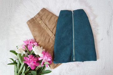 Brown and blue suede skirts and a bouquet of peonies. Fashionable concept, white fur on the background