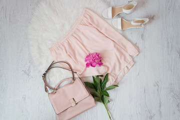 Pink blouse, bag, shoes and a bouquet of peonies. Fashionable concept, white fur on the background