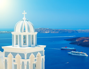 Fototapeta na wymiar Blue dome of famous church in Santorini with view on the caldera and cruise ships