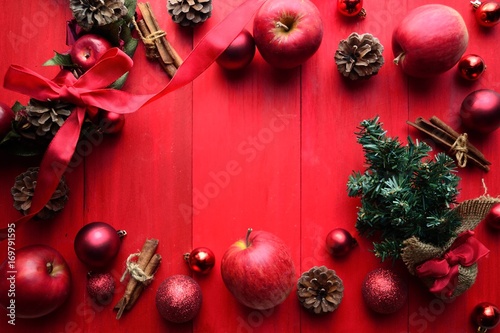 林檎のクリスマスリースとクリスマスツリー 赤色背景 Wall Mural Yonibunga
