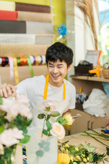 Smiling young asian florist man making bunch at flower shop