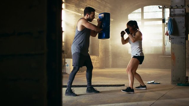 Athletic Woman Hits Punching Bag that Her Partner/ Trainer Holds. She's Professional Fighter and is Training in a Gym. Shot on RED EPIC-W 8K Helium Cinema Camera.
