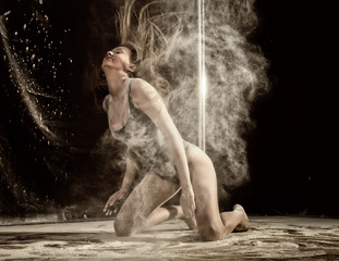 Beautiful expressive dencer dancing at studio with flour or smoke