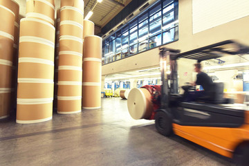 Gabelstapler transportiert Papierrollen in einer Druckerei im Lager - Bewegungsaufnahme Geschwindigkeit // Forklift truck transports paper rolls in a print shop in the warehouse