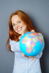 lachende frau zeigt eine weltkugel