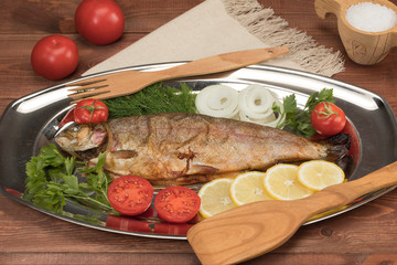 fish baked in foil on a tray with lemon greens and spices