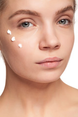 Obraz premium Gorgeous beautiful woman with cream face drops on her face. Studio photo. Beauty and skin care