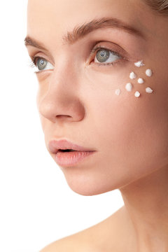 Woman with cream face drops on her face. Studio photo. Beauty and skin care