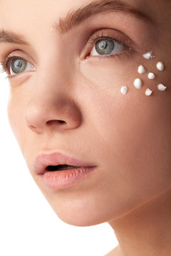 Woman with cream face drops on her face. Studio photo. Beauty and skin care