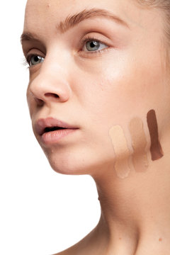 Gorgeous beautiful woman with stripes of different type of cream on face. Studio photo. Beauty and skin care