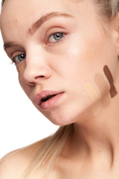 Beautiful woman with stripes of different type of cream on face. Studio photo. Beauty and skin care