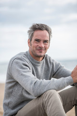 Portrait of a Gray haired man sitting on a rock at the beach