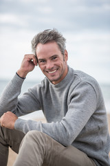 Portrait of a Gray haired man sitting on a rock at the beach