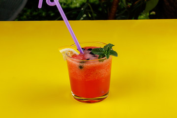 Watermelon smothie and slices with lemon on yellow background