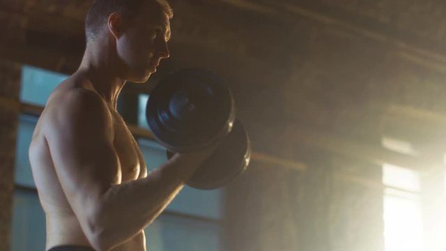 Handsome Muscular Shirtless Man Doing Biceps Curls with Dumbbells, as Part of His Bodybuilding Gym Training. Shot on RED EPIC-W 8K Helium Cinema Camera.