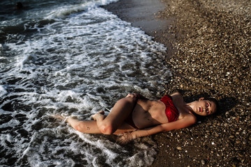 sexy girl of Asian appearance in her swimsuit on the sea with sand, fashion