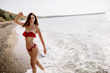 sexy girl of Asian appearance in her swimsuit on the sea with sand, fashion