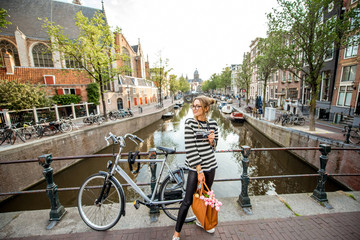 Cityscape view on the water channel with young woman tourist standing on the bridge in Amsterdam...