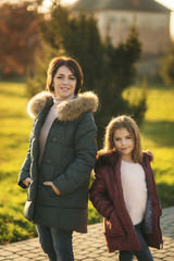 Fototapeta premium Little girl with mother walking in the park in autumn. Golden autumn.
