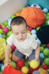 Fototapeta na wymiar Little boy in playground. Caucasian little boy sitting on colored ball.