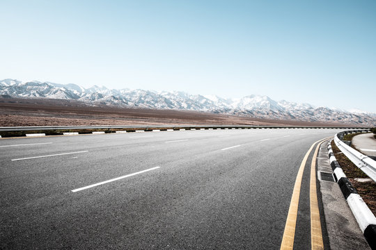 empty road with snow mountains in blue sky