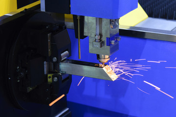 The CNC fiber laser cutting machine cutting the steel square pipe with the sparking light.The fire flame from the fiber laser cutting machine.