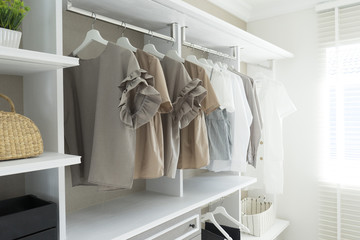 White wardrobe with shirts and pants hanging 