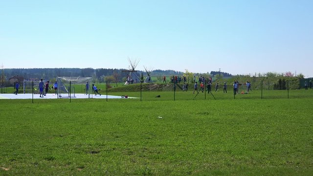 Boys play floorball and football on a sunny day on a school playground