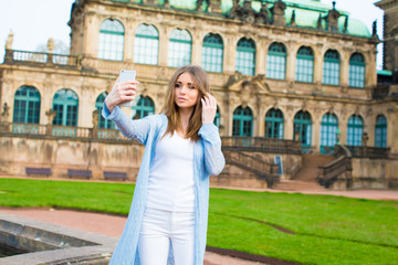 Fototapeta premium Girl makes photos shots of european city Dresden and selfie of background old German town