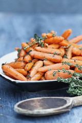 Honey Glazed Baby carrots with wooden spoon for Rosh Hashanah or Thanksgiving Day. Extreme shallow depth of field with selective focus on carrots in foreground of dish.