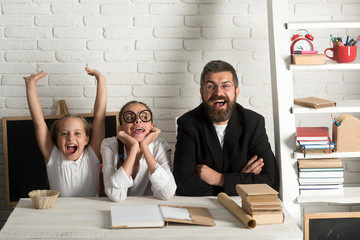 Fototapeta premium Girls and bearded man sit at desk with books