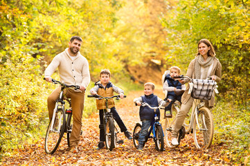 Young family in warm clothes cycling in autumn park