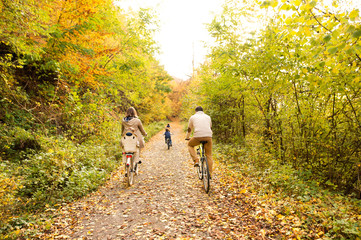 Fototapeta premium Young family in warm clothes cycling in autumn park