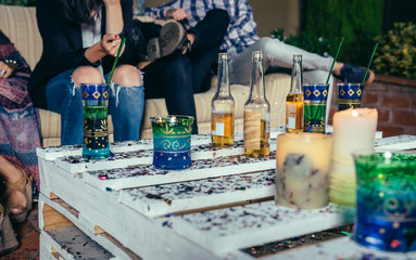 Close up of beverages over pallets table with confetti in a outdoors party with people talking in the background