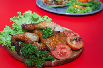 grilled wing and Drumstick chicken on wooden plate on red background