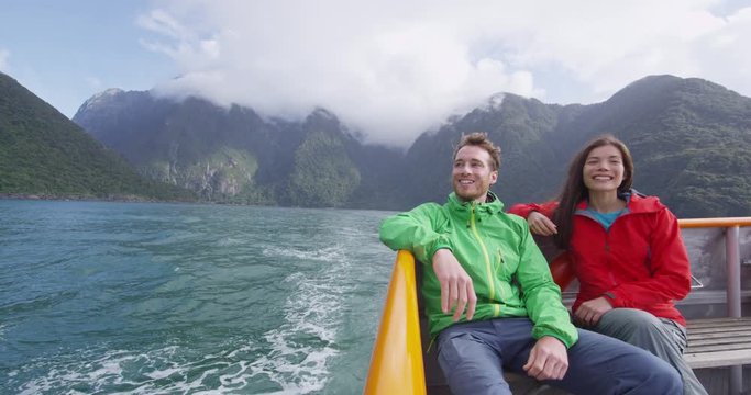 Cruise ship tourists on boat tour in Milford Sound, Fiordland National Park, New Zealand. Happy romantic couple on sightseeing travel honeymoon on New Zealand South Island. RED EPIC SLOW MOTION.
