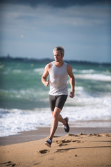 A man in sportswear is running on the beach