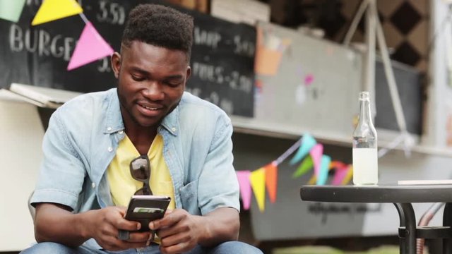 african american man with smartphone at food truck