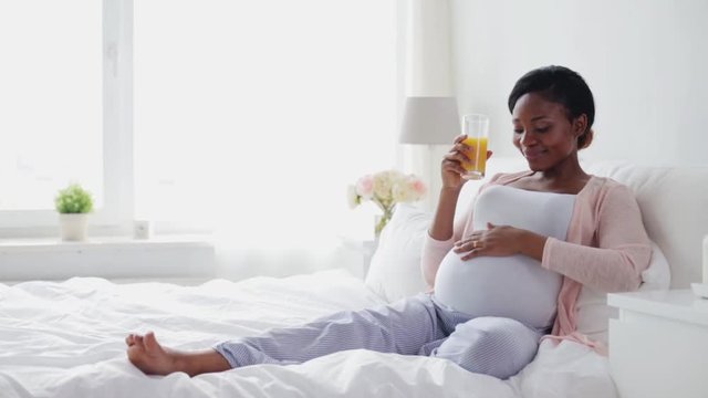happy pregnant woman drinking fresh orange juice