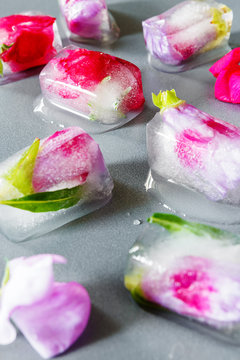 Frozen flowers in ice cubes for cosmetic procedures on a dark background with drops of water