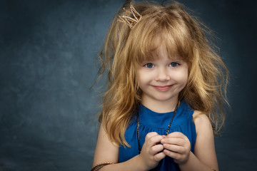 charming little girl with her hair in the blue dress and the crown Princess looks in the frame © olgamazina